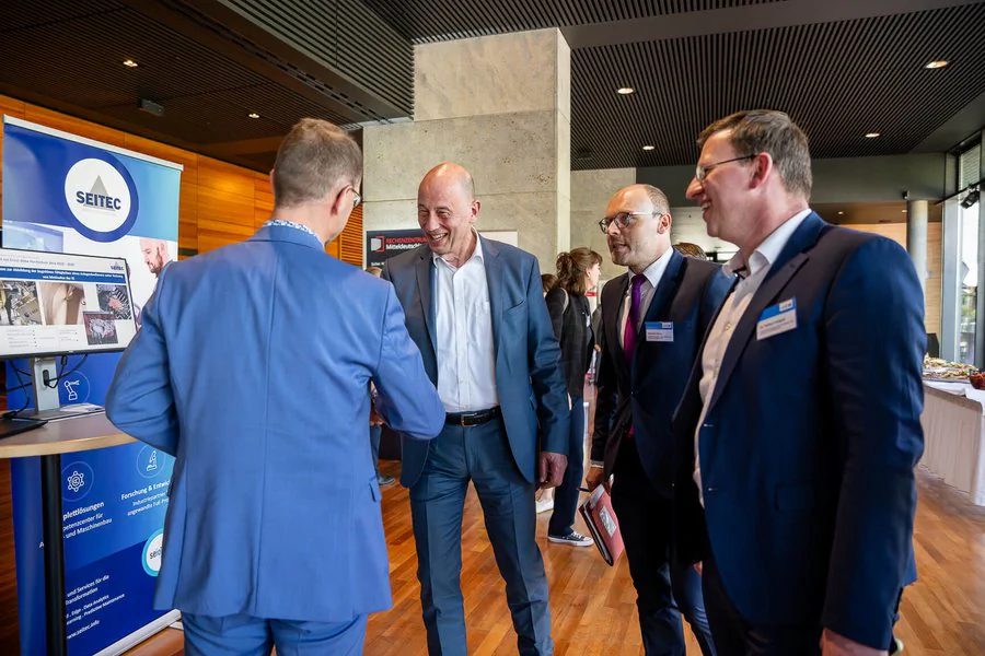 Foto: vier Männer stehen an einem Messestand (des Unternehmens Seitec), ein Mitarbeiter von Seitec, Wolfgang Tiefensee (Thüringens Wirtschaftsminister) und zwei Mitarbeiter der LEG