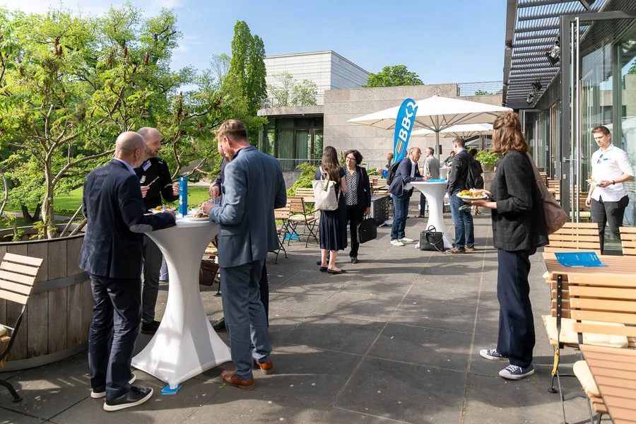 Gruppe von Leuten versammelt sich um Tische bei einem Outdoor-Event.