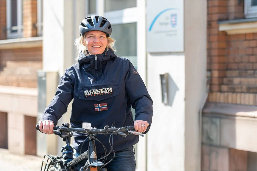 Eine Frau mit Helm steht neben einem Fahrrad