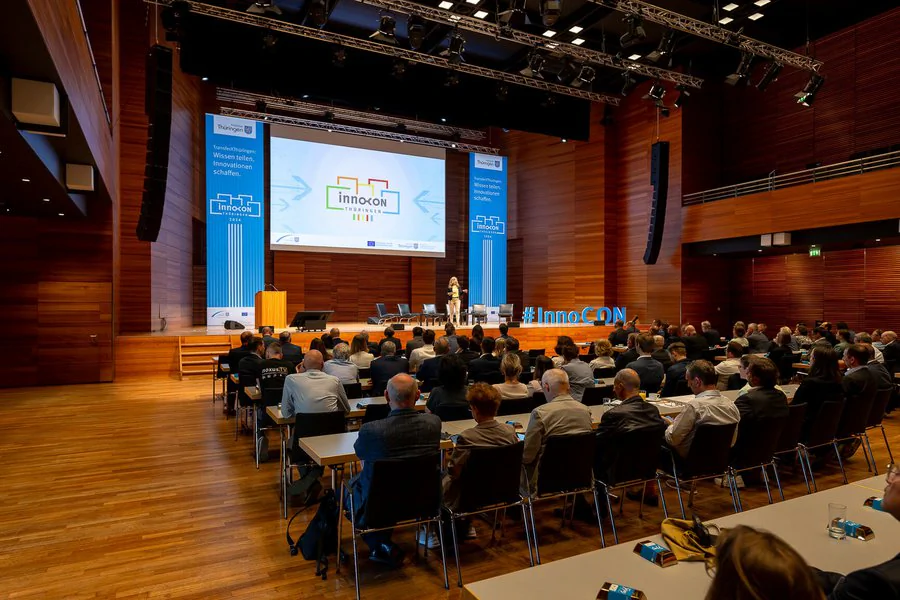 Menschen sitzen an Tischen in einem großen Auditorium