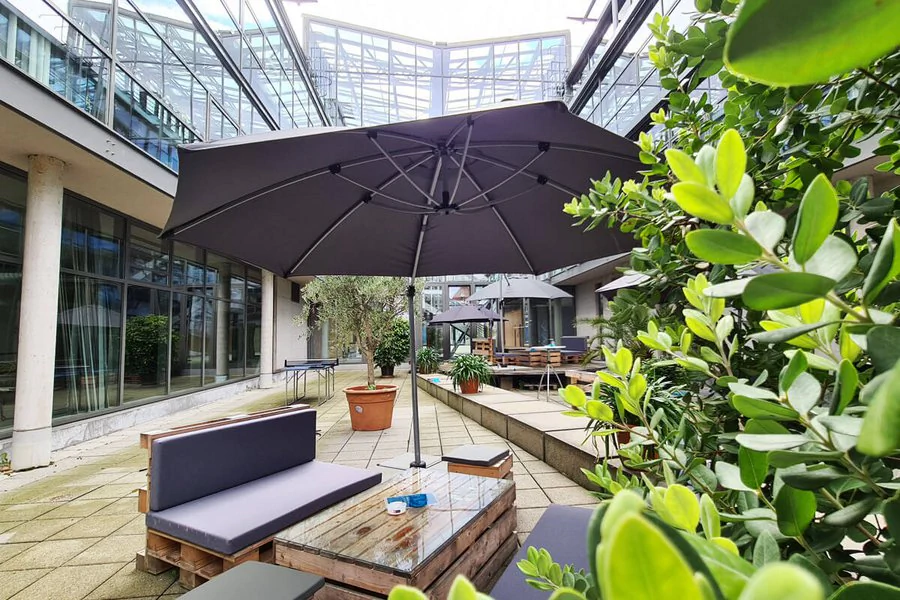 Eine Terrasse mit einem Tisch und Stühlen, die unter einem Sonnenschirm stehen, lädt zum Entspannen ein.