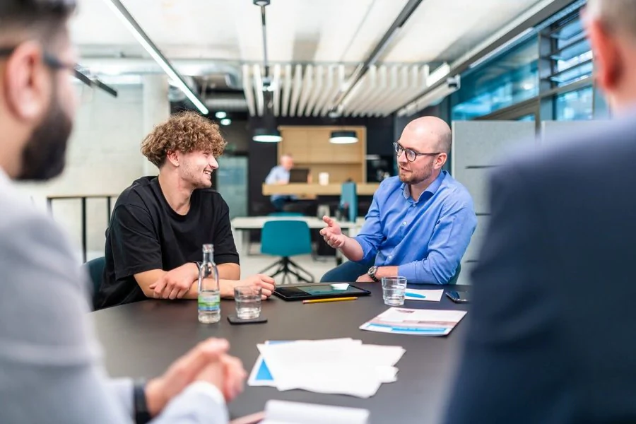 Vier Männer sitzen um einen Tisch und führen ein angeregtes Gespräch miteinander.