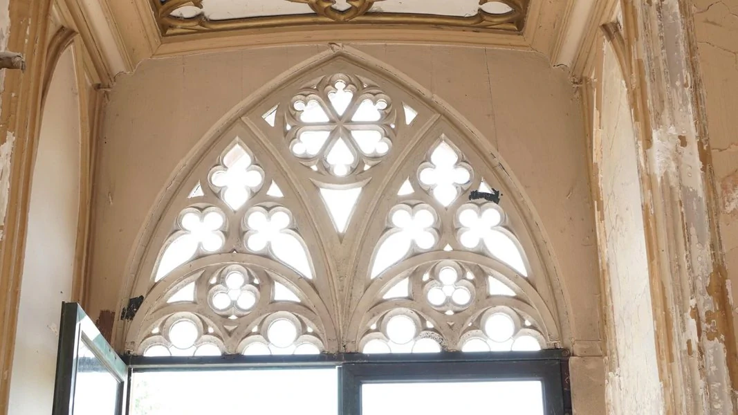 Ein Fenster mit gotischem Design, das kunstvolle Verzierungen und spitz zulaufende Bögen zeigt.