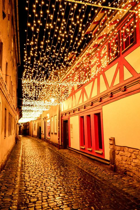 Eine mit Lichtern gesäumte Kopfsteinpflasterstraße bei Nacht.