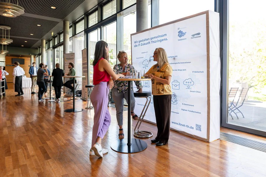 Foto, drei Frauen unterhalten sich an einem Messestand