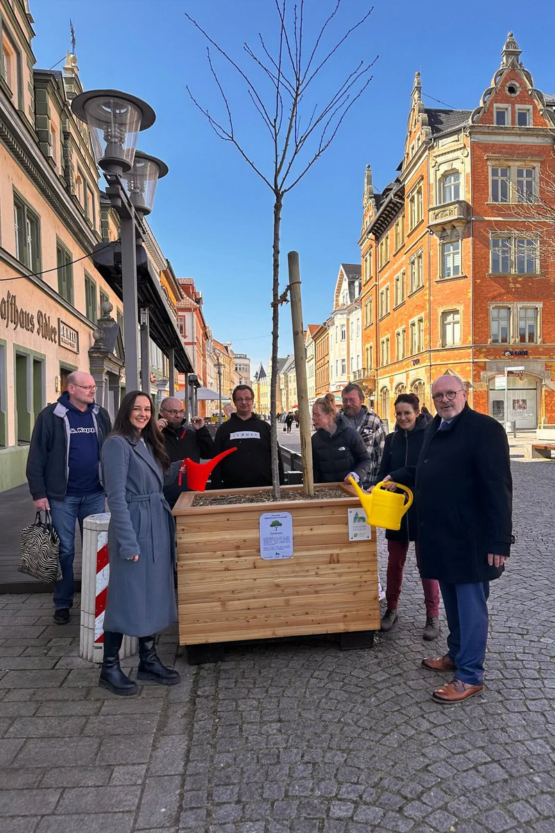 Projektbeteiligte gießen einen Baum der Wanderbaumallee in Rudolstadt