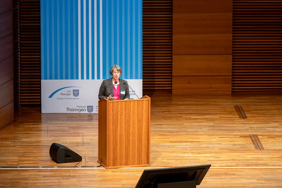 Foto: Frau hält Rede vor einem Publikum am Rednerpult.