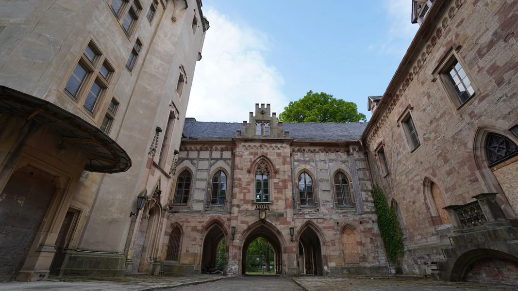 Der malerische Innenhof eines Schlosses, geprägt von einem eleganten Steinbogen und umgeben von alten Steinmauern.
