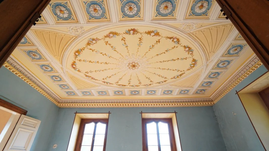 Das Innere eines verlassenen Schlosses mit blauen Wänden und aufwändiger Stuckdecken