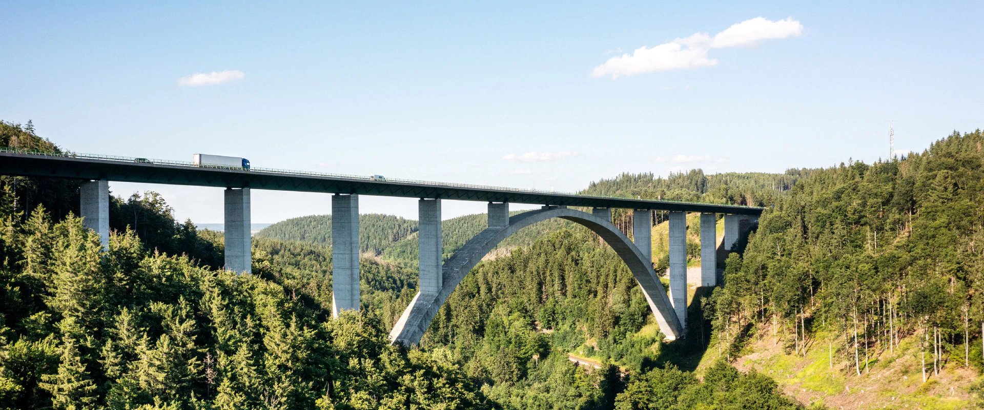 Eine Brücke, die über ein Tal in den Bergen spannt, umgeben von majestätischen Berglandschaften.