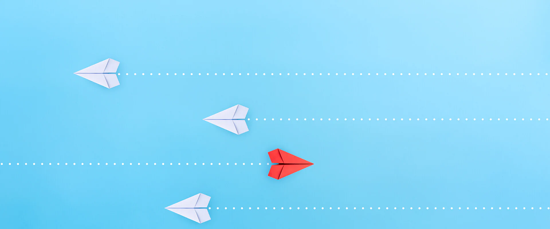 Bildbeschreibung / description: vier Papierflugzeuge von oben, die drei weißen fliegen nach links, der rote nach rechts