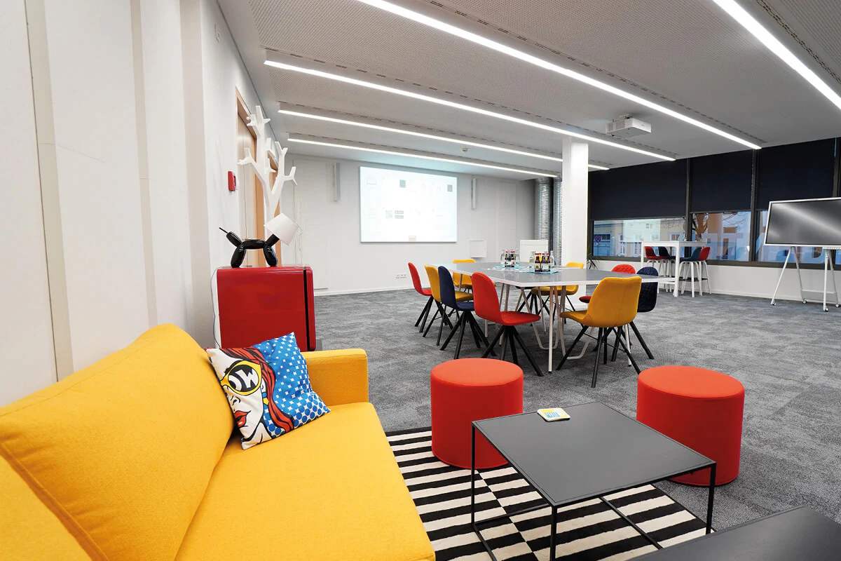Bildbeschreibung / description: Gemütlicher Beratungsraum mit einem gelben Sofa, roten Stühlen, Tischen und weißen Wänden