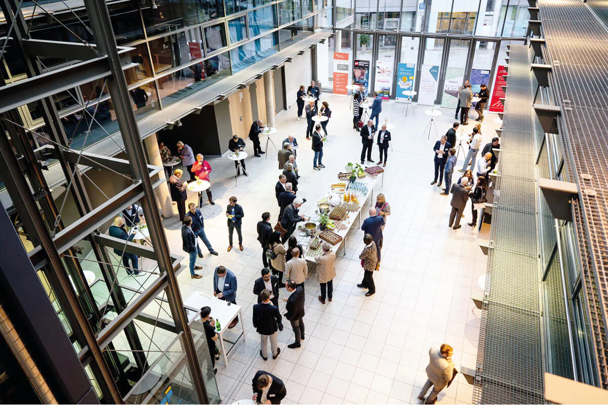 Bildbeschreibung / description: Eine große Gruppe von Menschen sitzt in Stühlen in einem Raum und diskutiert angeregt miteinander.