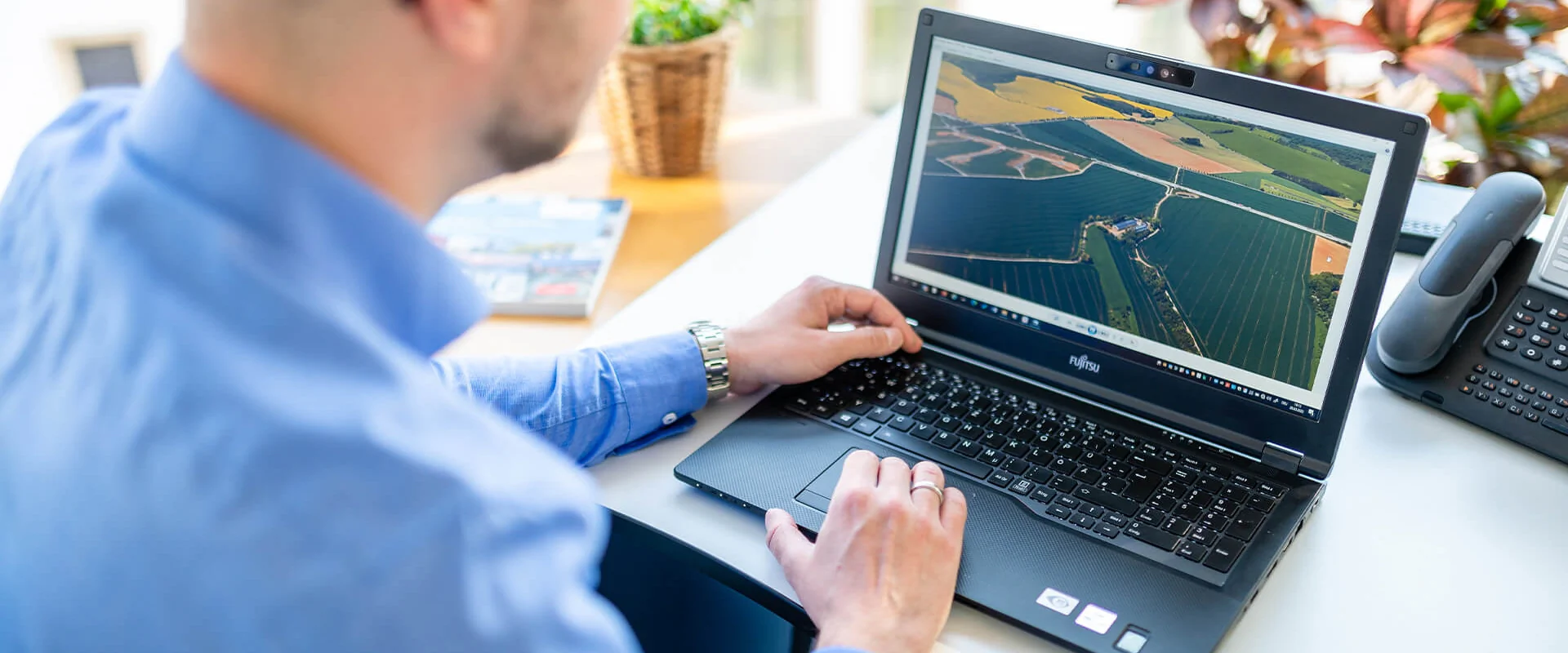 Service Bildbeschreibung / description: Ein Mann arbeitet am Laptop und betrachtet landwirtschaftliche Informationen auf einer Farm.