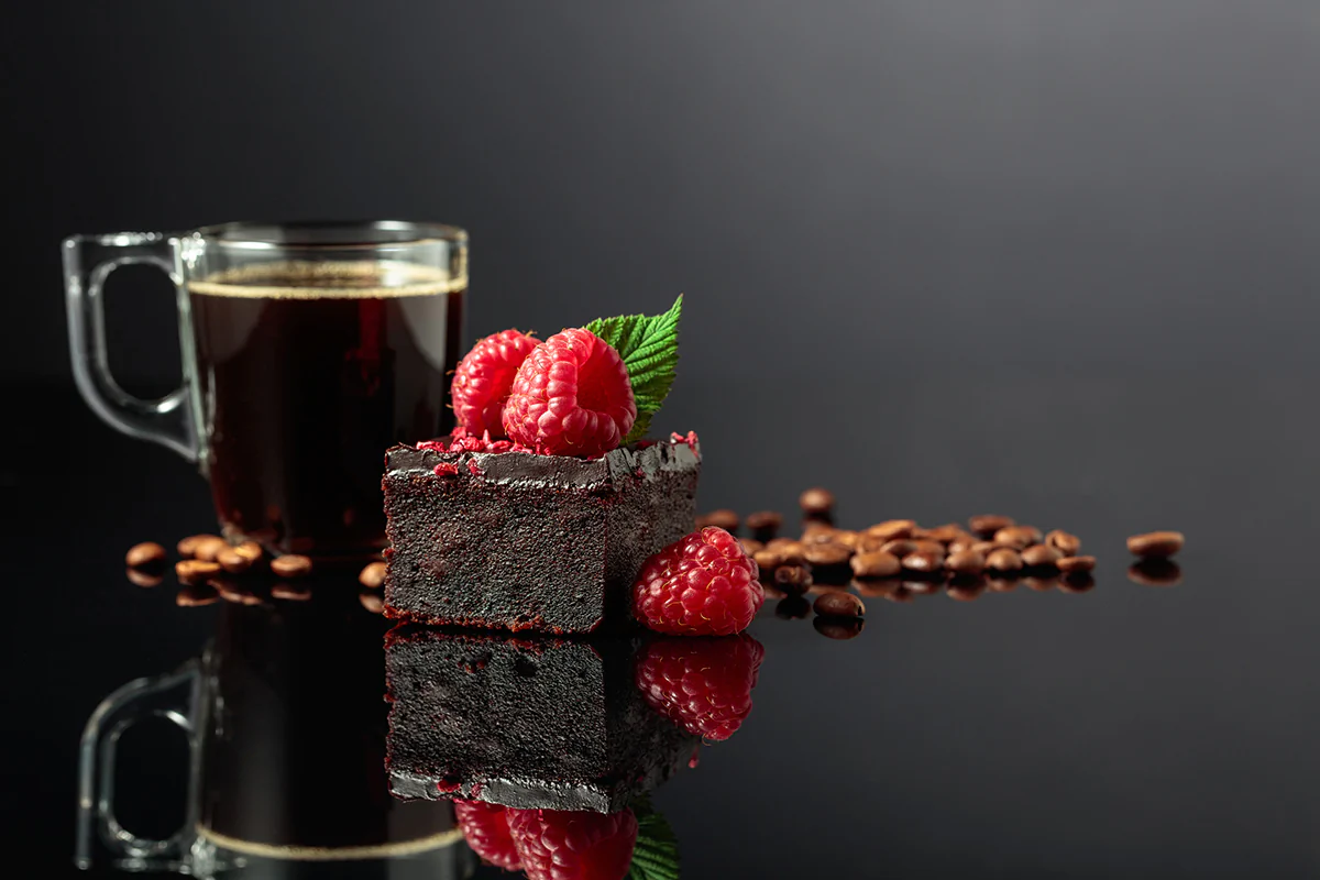 Schokoladenkuchen mit frischen Himbeeren und schwarzem Kaffee